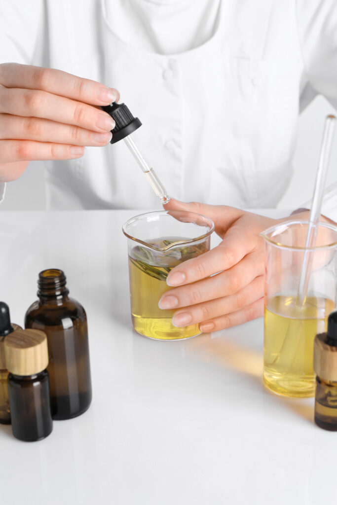 Scientist holding a pipette over a beaker with yellow liquid inside it