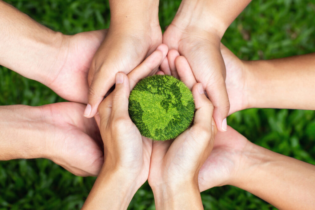 Hands holding a globe made of grass